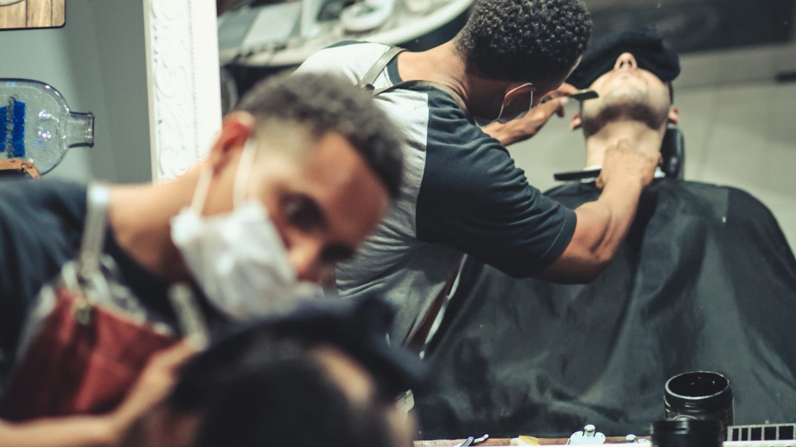 A barber giving a straight razor shave in the shop